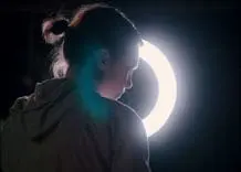 A still from the short film, "The Golden Age." It shows a person in profile illuminated by a ring of light.
