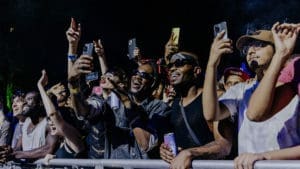 A crowd of diverse patrons smiling, watching and recording on their phones at a SummerStage concert.