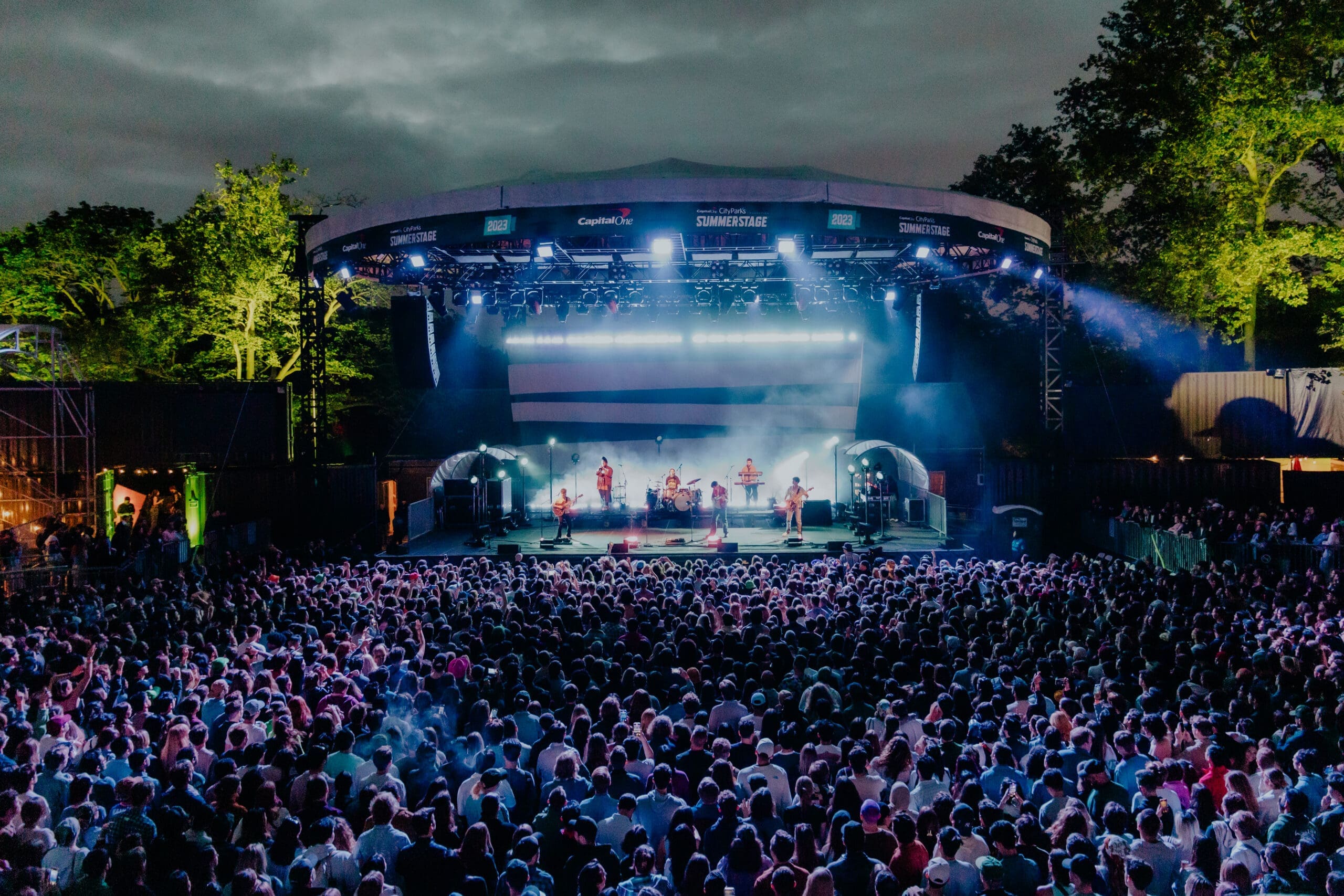 a band performing on stage with a large crowd of people