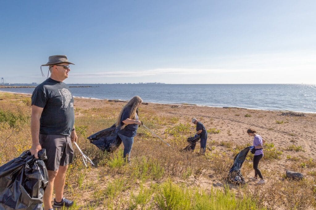 a group of people cleaning up trash on a beach