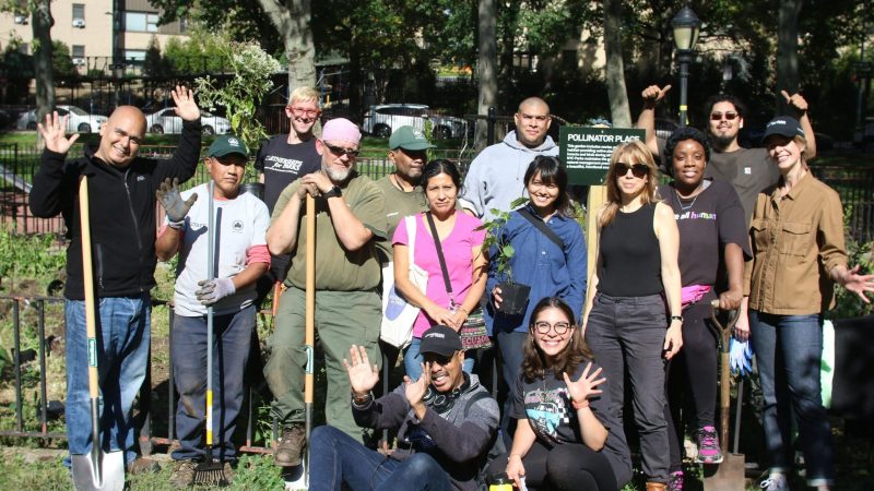 a group of people posing for a photo in a park with shovels