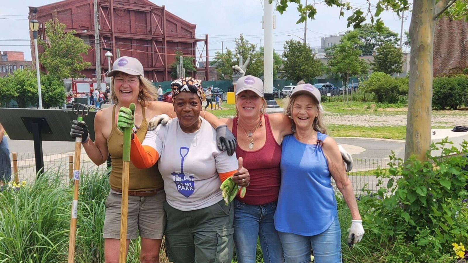 a group of women posing for a photo with shovels in a garden