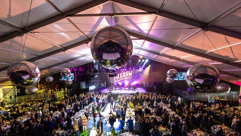 a large group of people in a large room with a stage and a stage with a large mirror ball from the ceiling