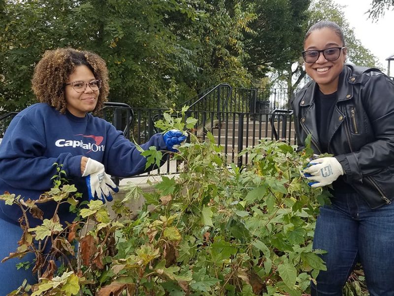 Two Corporate Opportunity volunteers participating in an It's My Park project in a NYC park pose and smile for the camera.