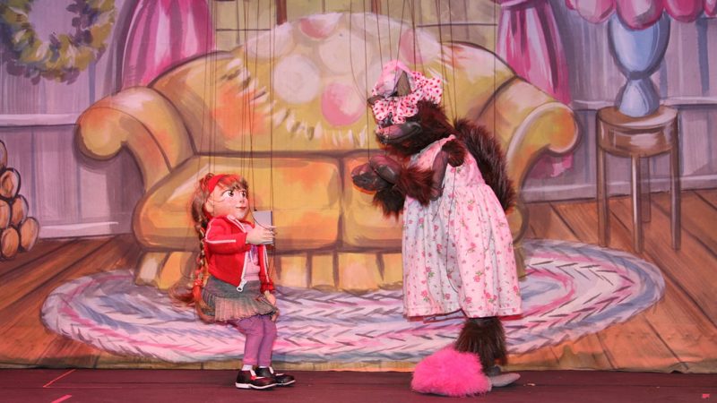 A photo from a performance of Little Red's Hood at the Swedish Cottage Marionette Theatre. It features the titular Little Red with a wolf puppet disguised as grandma.